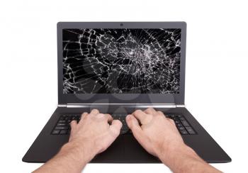 Man working on a laptop with a broken screen, black