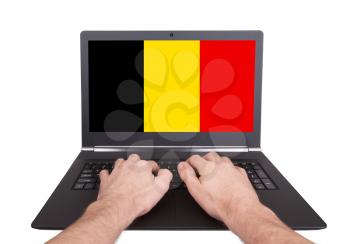 Hands working on laptop showing on the screen the flag of Belgium