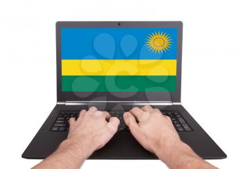 Hands working on laptop showing on the screen the flag of Rwanda