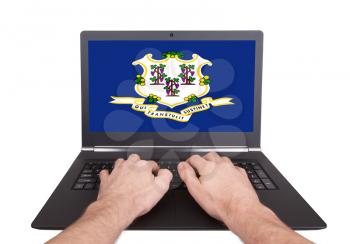 Hands working on laptop showing on the screen the flag of Connecticut