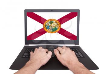 Hands working on laptop showing on the screen the flag of Florida