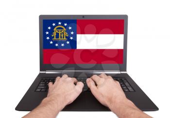 Hands working on laptop showing on the screen the flag of Georgia