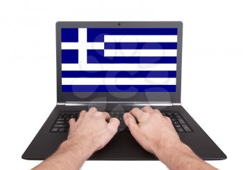Hands working on laptop showing on the screen the flag of Greece