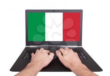 Hands working on laptop showing on the screen the flag of Italy