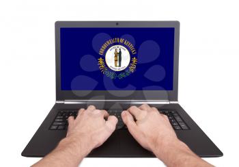 Hands working on laptop showing on the screen the flag of Kentucky