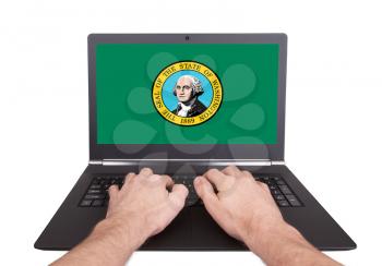 Hands working on laptop showing on the screen the flag of Washington