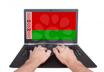 Hands working on laptop showing on the screen the flag of Belarus