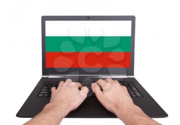 Hands working on laptop showing on the screen the flag of Bulgaria