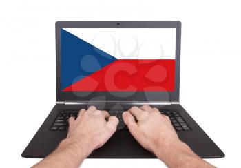Hands working on laptop showing on the screen the flag of Czech Republic