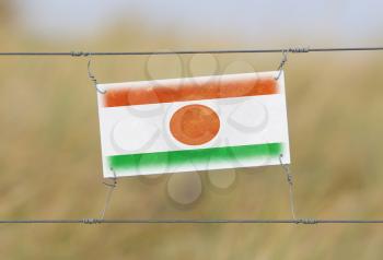 Border fence - Old plastic sign with a flag - Niger