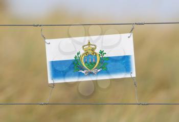 Border fence - Old plastic sign with a flag - San Marino