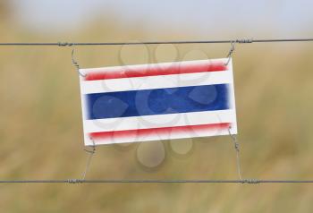 Border fence - Old plastic sign with a flag - Thailand