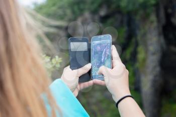 Woman photographing a waterfall with a mobile phone - Iceland