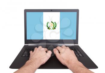 Hands working on laptop showing on the screen the flag of Guatemala