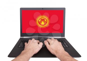 Hands working on laptop showing on the screen the flag of Kyrgyzstan