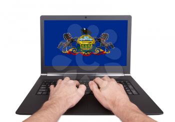 Hands working on laptop showing on the screen the flag of Pennsylvania
