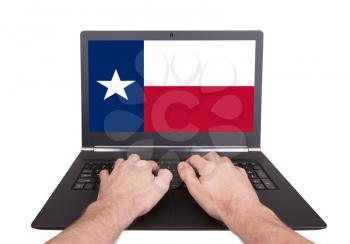 Hands working on laptop showing on the screen the flag of Texas