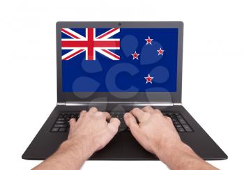 Hands working on laptop showing on the screen the flag of New Zealand