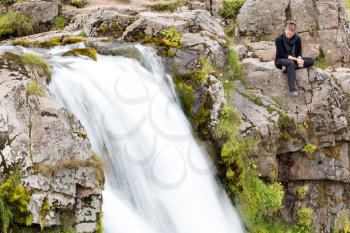 Woman at Kirkjufellsfoss waterfall near the Kirkjufell mountain on the north coast of Iceland's Snaefellsnes peninsula