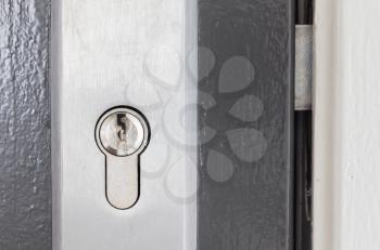 Cylinder lock closeup, shiny chrome, cylinder in a grey door