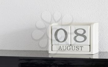 White block calendar present date 8 and month August on white wall background
