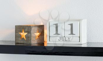 White block calendar present date 11 and month July on white wall background