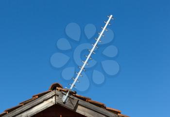 Simple old antenna on a roof, blue background
