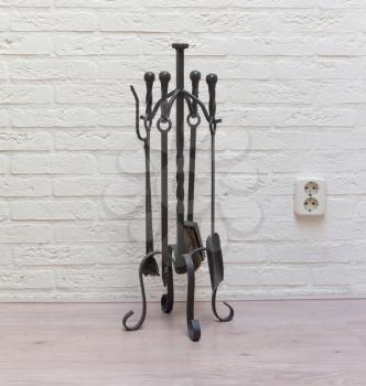 Set of fireplace accessories isolated against a white brick wall