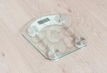 Glass weight scale standing on a wooden floor