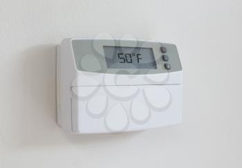 Vintage digital thermostat hanging on a white wall - Covert in dust - 50 degrees fahrenheid