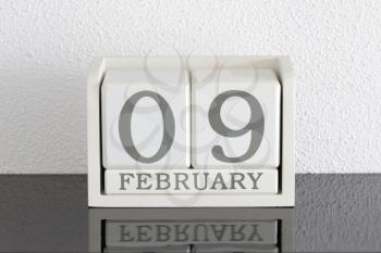 White block calendar present date 9 and month February on white wall background