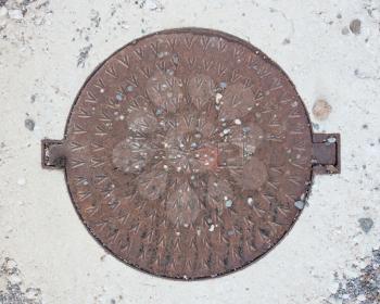 Circle steel manhole cover or metal sewer on a street in Greece