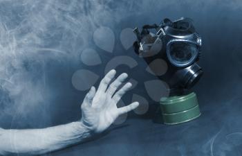 Man in room filled with smoke, trying to reach for vintage gasmask - Isolated on black - Blue smoke