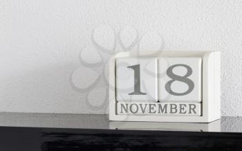 White block calendar present date 18 and month November on white wall background
