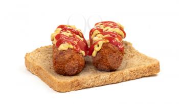 Brown crusty dutch kroket with mustard topping isolated, on a piece of bread, on a white background