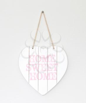 Text home sweet home in a heart-shaped signboard - Hanging on a white wall