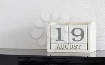 White block calendar present date 19 and month August on white wall background