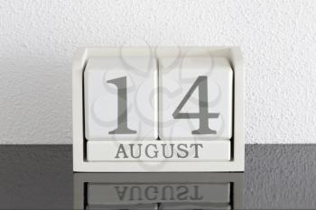 White block calendar present date 14 and month August on white wall background