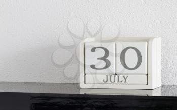 White block calendar present date 30 and month July on white wall background