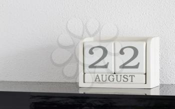White block calendar present date 22 and month August on white wall background
