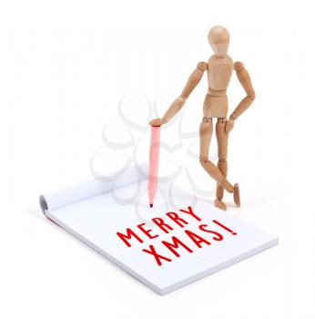 Wooden mannequin writing in a scrapbook - Merry xmas