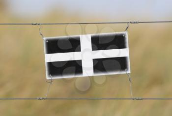Border fence - Old plastic sign with a flag - Cornwall