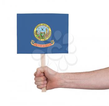 Hand holding small card, isolated on white - Flag of Idaho