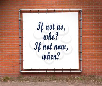 Large banner with inspirational quote on a brick wall - If not us, who? If not now, when?