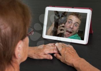 Senior woman with tablet contacting her family