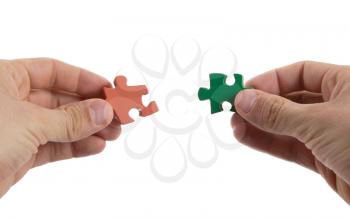 Close-up of hands trying to connect big jigsaw puzzle pieces over white background