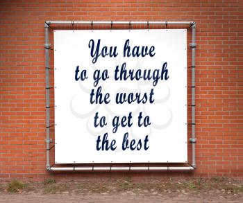 Large banner with inspirational quote on a brick wall - You have to go through the worst...