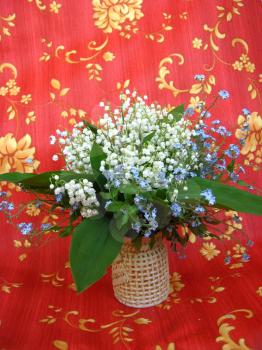 Beautiful bouquet of lilies of the valley and blue flowers on a red background