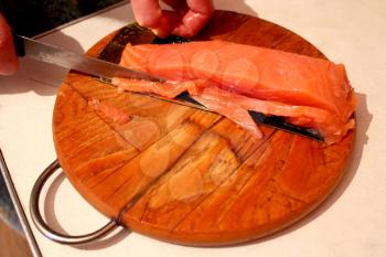 image of hand cuts slices of red fish