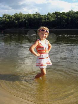 little girl standing in the beautiful river